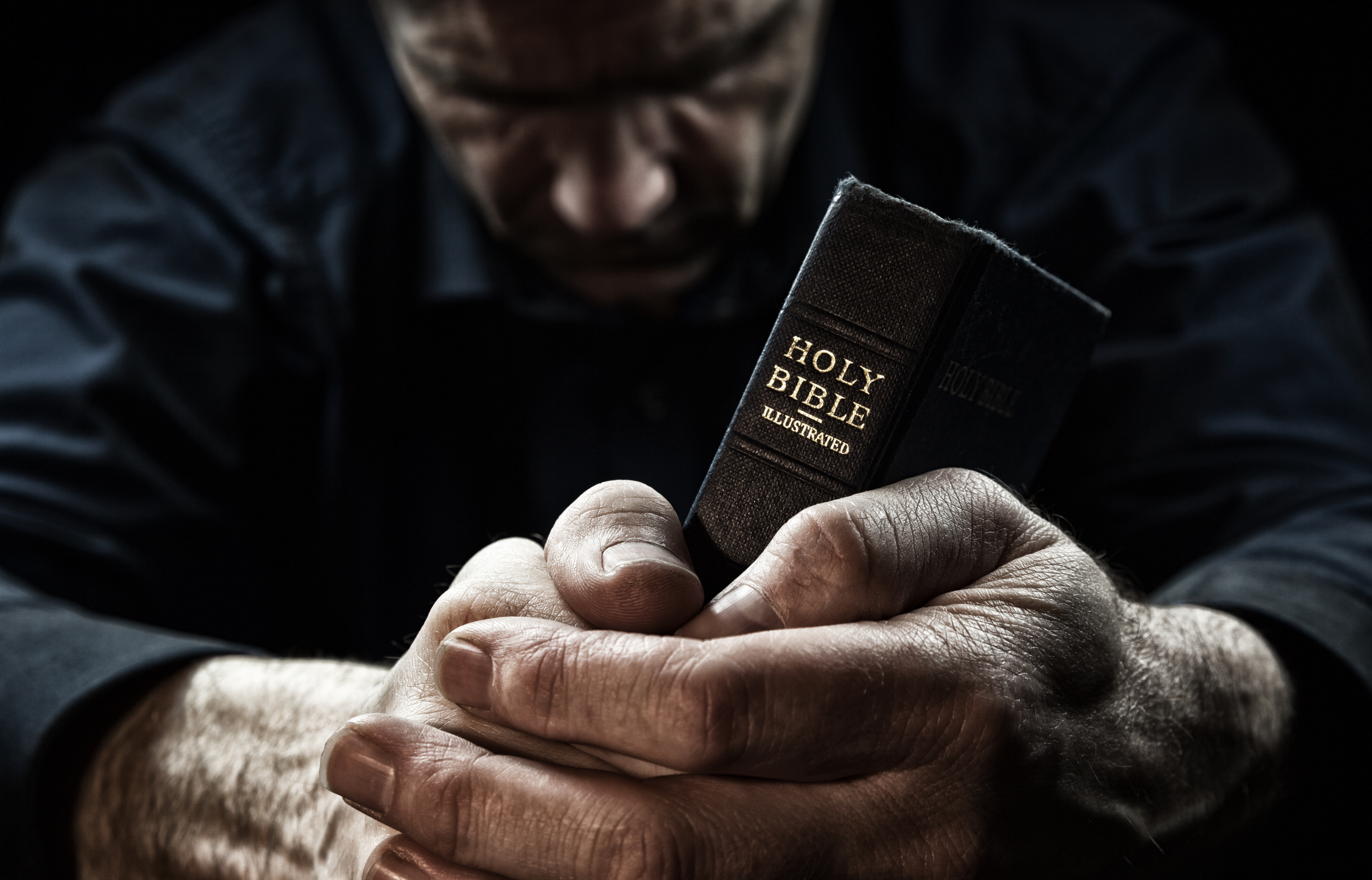 A Man Praying Holding A Holy Bible The Broken Assembly